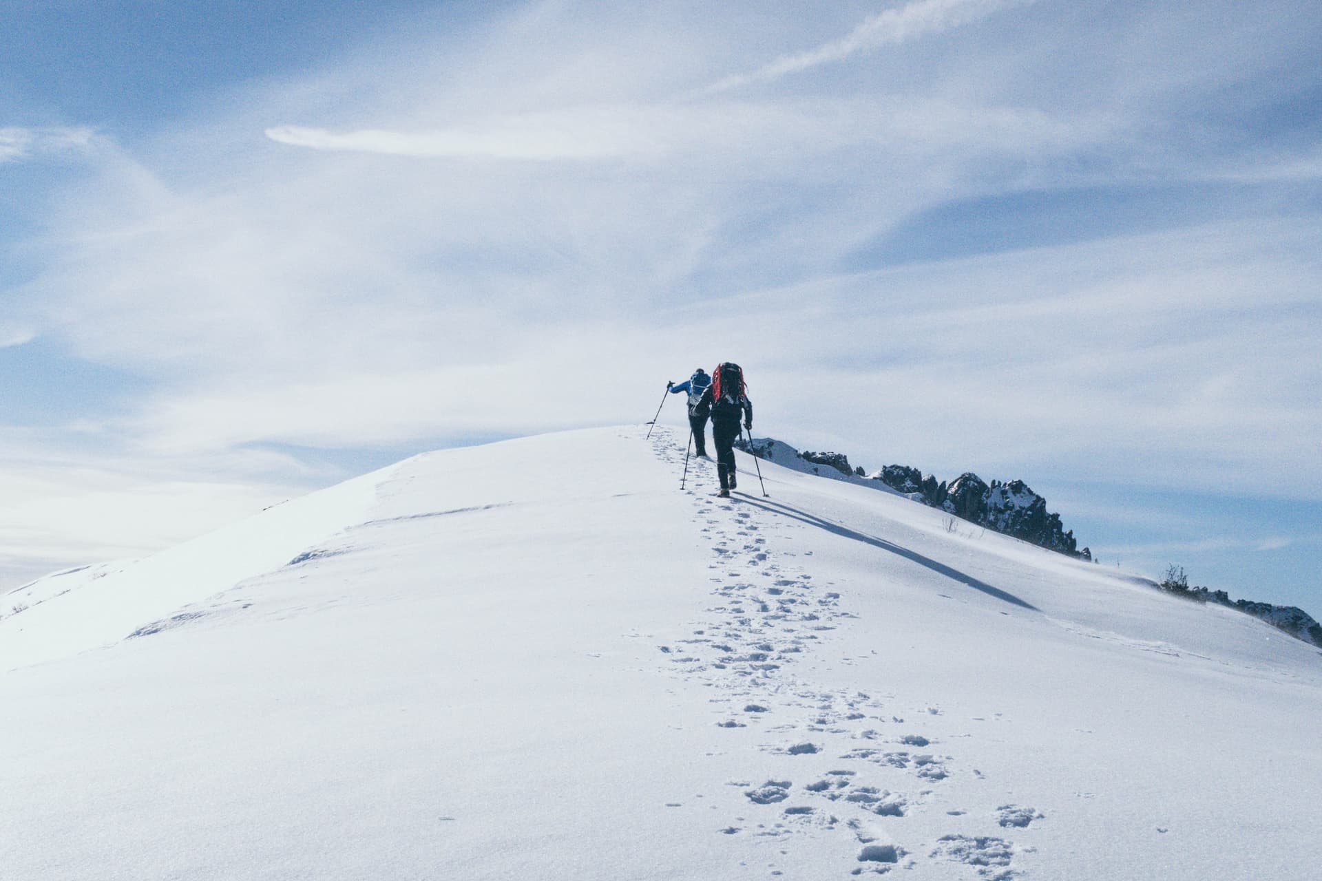 Friends hiking up snowy mountain