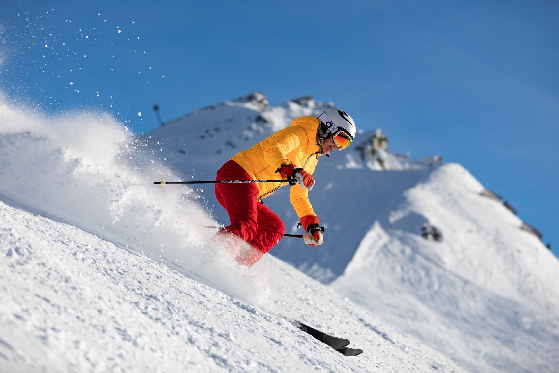 Woman in orange jacket skiing down ski slope